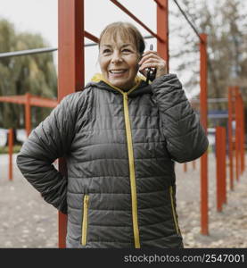 smiley older woman taking phone outdoors