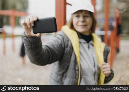 smiley older woman taking selfie outdoors while working out