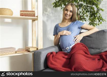 smiley pregnant businesswoman sitting couch holding her belly