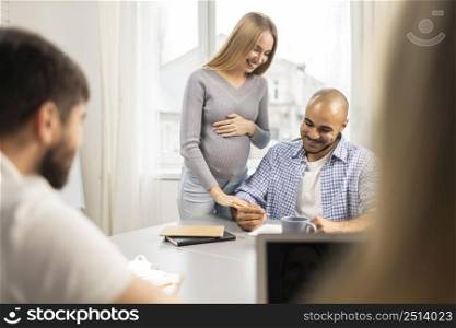 smiley pregnant businesswoman with male coworkers office