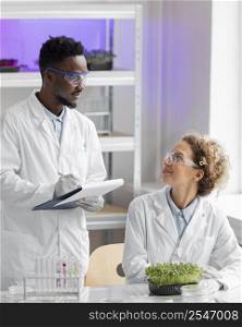 smiley researchers laboratory checking plant writing clipboard