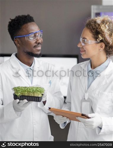 smiley researchers laboratory with safety glasses plant