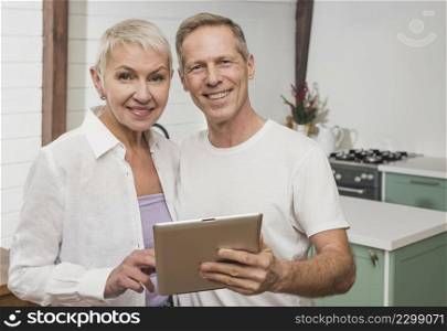 smiley senior couple holding their tablet