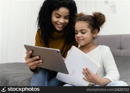 smiley teenage girl helping sister using tablet online school