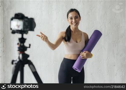 smiley vlogger holding fitness mat