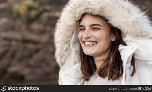 smiley woman beach with winter jacket copy space