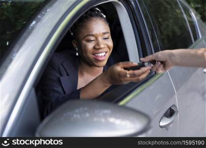 smiley woman being handed keys her new car