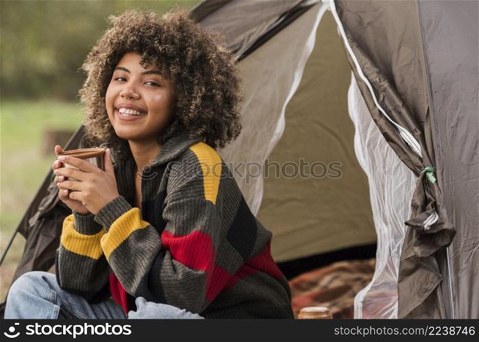 smiley woman camping outdoors with tent