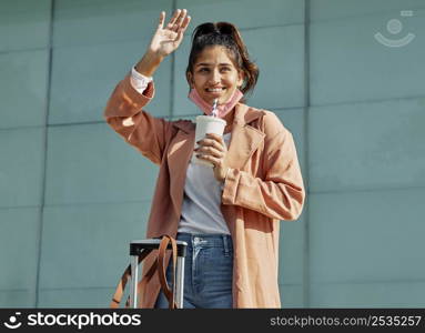 smiley woman during pandemic airport with medical mask luggage