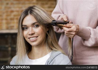 smiley woman getting her hair straightened home