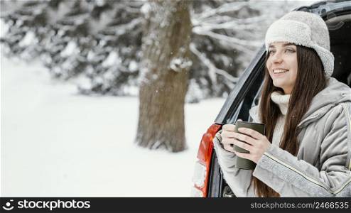 smiley woman having warm drink while road trip with copy space