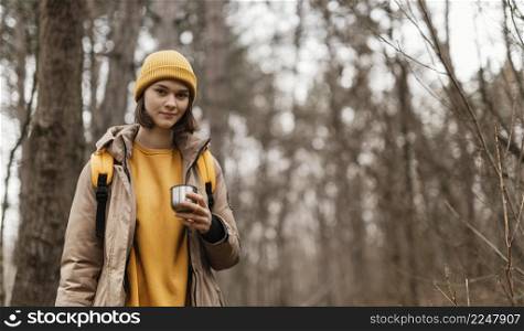 smiley woman holding cup forest