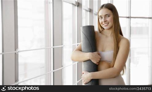 smiley woman holding yoga mat