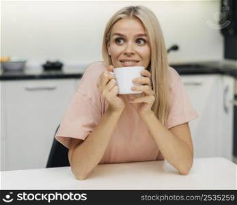 smiley woman home during pandemic having cup coffee