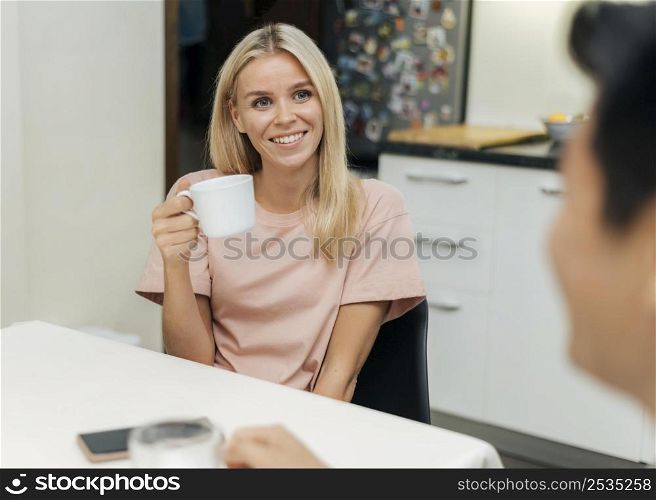 smiley woman home during pandemic having cup coffee with her boyfriend