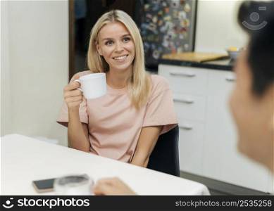 smiley woman home during pandemic having cup coffee with her boyfriend