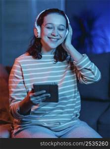 smiley woman home using headphones tablet