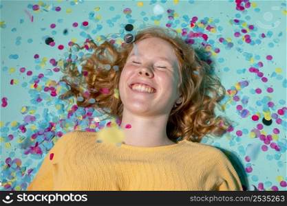 smiley woman lying floor with confetti around her