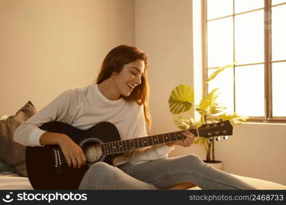 smiley woman playing guitar home bed