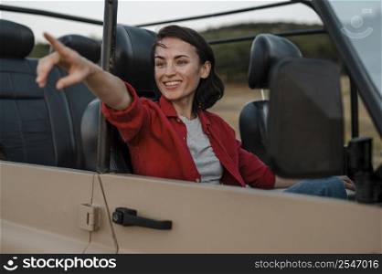 smiley woman pointing while traveling alone by car