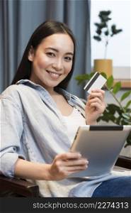 smiley woman posing while holding tablet credit card