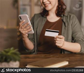 smiley woman using her smartphone with credit card home