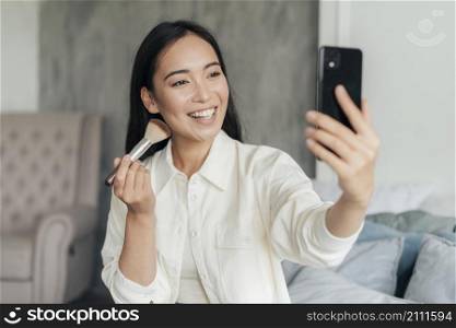 smiley woman vlogging with make up brush
