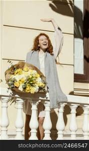 smiley woman waving outdoors with bouquet spring flowers