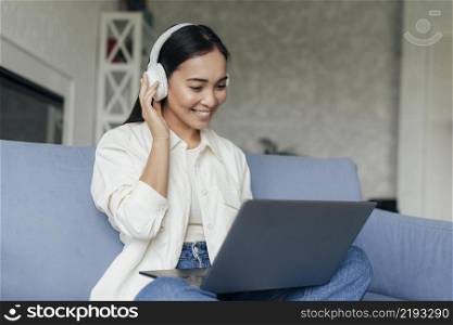 smiley woman with headphones working laptop