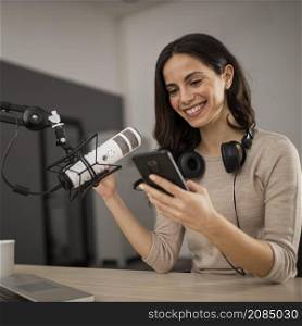 smiley woman with smartphone microphone radio studio