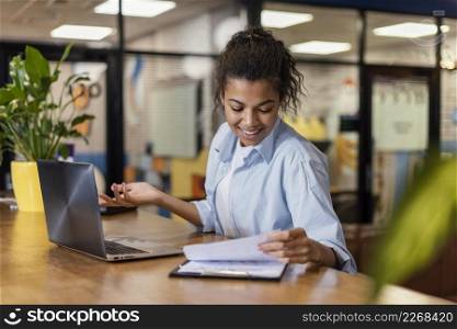 smiley woman working office with papers laptop
