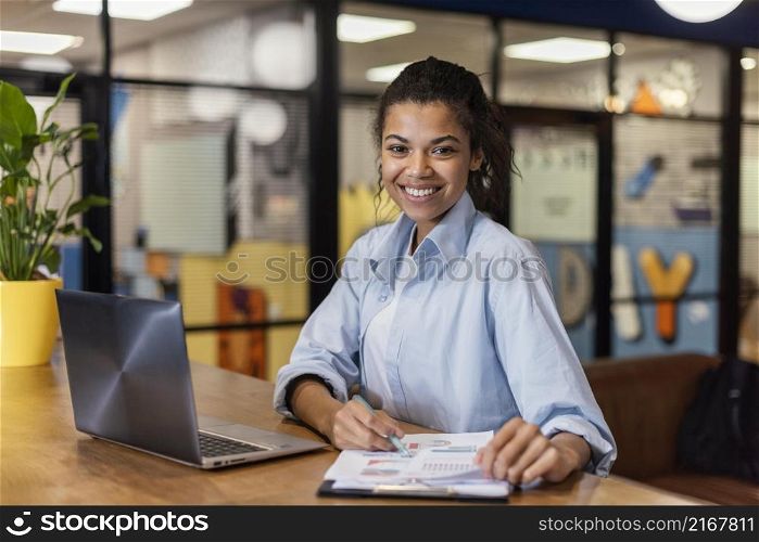 smiley woman working with laptop papers office