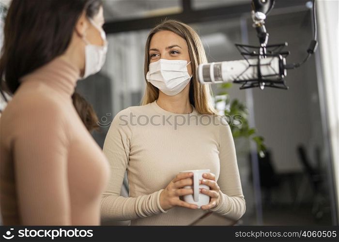 smiley women doing radio together while wearing medical masks