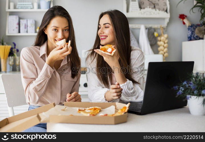 smiley women eating pizza after working