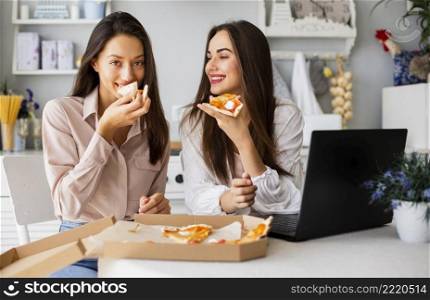 smiley women eating pizza after working
