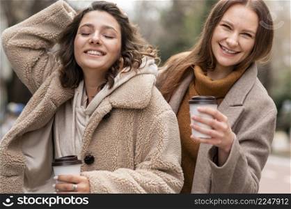 smiley women with coffee cups outdoors