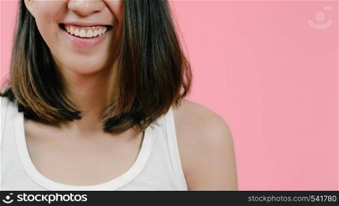 Smiling adorable Asian female with positive expression, smiles broadly, dressed in casual clothing and looking at the camera over pink background. Happy adorable glad woman rejoices success.