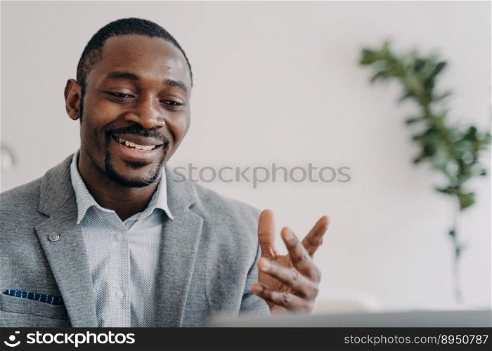 Smiling african american businessman holding a video call with customers on laptop. Optimistic black male businessperson or coach gives online consultation, advises clients.. Smiling african american businessman holding a video call with customers on laptop, advises clients