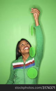 Smiling African-American mid-adult woman in green coat on green background holding green mobile.