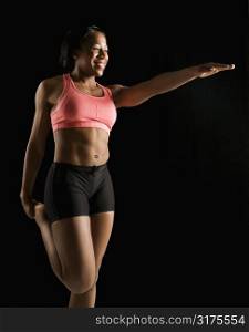 Smiling African American young adult woman standing and stretching.