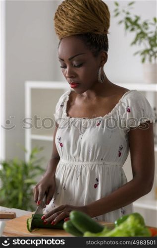 Smiling african woman chopping vegetables for salad at kitchen