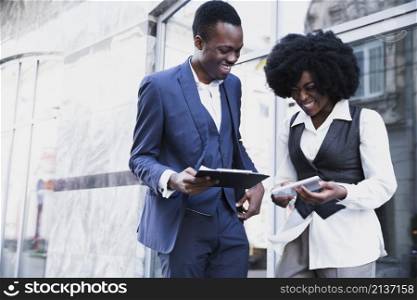 smiling african young businessman businesswoman holding clipboard digital tablet