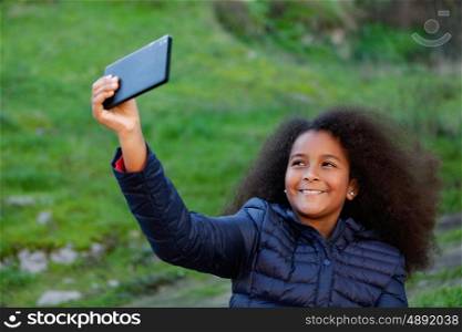 Smiling afro child with a mobile in the park taking a photo himself