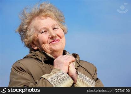 Smiling aged woman with hands on sky