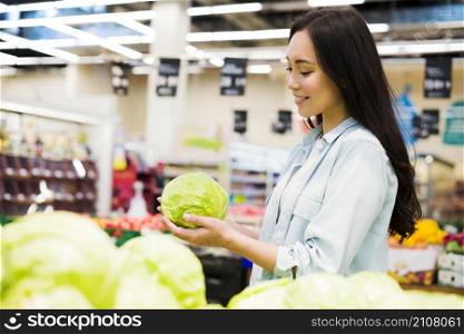smiling asian woman choosing cabbage market