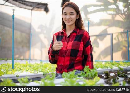 Smiling Asian woman farmer in greenhouse hydroponic organic.Small business entrepreneur and organic vegetable farm and healthy food concept