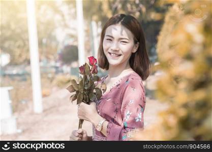 Smiling asian women holding red roses at park