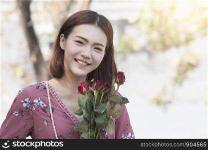 Smiling asian women holding roses in park