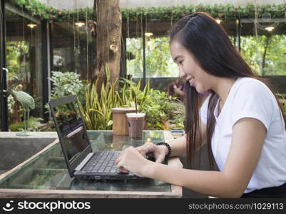 smiling asian women working with laptop in cafe