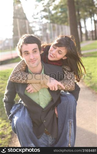 Smiling At Her Boyfriend As He Gives Her A Piggyback Ride Through The Park